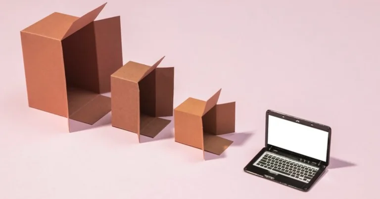 Drie geopende kartonnen dozen naast een laptop